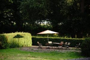 a table and chairs with an umbrella in a garden at See-h-Stueck in Himmelpfort