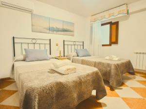 two beds in a room with two tables at Casa Rural Los Mayorales II Apartamento in La Garrovilla