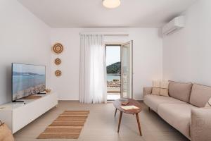 sala de estar blanca con sofá y TV en SeaView Apartment 1, en Samos