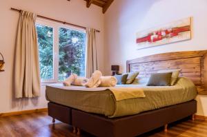 um quarto com uma cama grande com dois bichos de peluche em BOG Apart Foresta - A minutos del cerro bayo em Villa La Angostura