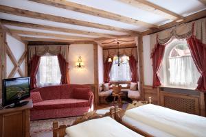 a bedroom with a couch and a chair and a tv at Hotel Colbricon Beauty & Relax in San Martino di Castrozza