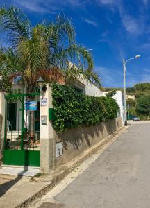 a building with a palm tree next to a street at B&B Scala dei Turchi Beach in Realmonte