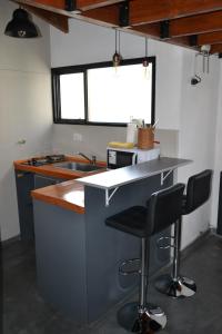 a kitchen with a counter and two bar stools at La Balconada by DOT Boutique in Villa Pehuenia