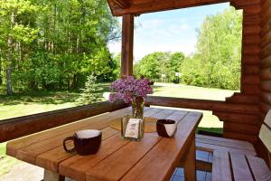 einen Holztisch mit einer Blumenvase auf der Veranda in der Unterkunft Sodyba Paštys in Vozgėliai