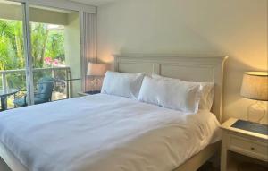 a bedroom with a white bed and a balcony at Walkable to Beach, Restaurants & Shops. Remodeled! in Wailea