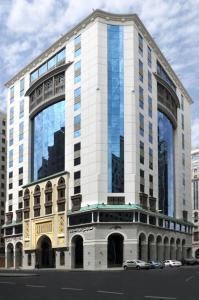 a tall white building with windows on a city street at Ruve Al Madinah Hotel in Medina