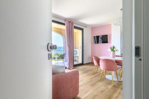 - un salon avec une table et une chambre rose dans l'établissement Casa Vacanze Maddalena - Palazzetto sul lago - Diamante Rosa, à Marta