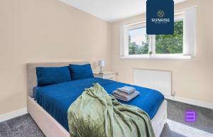 Un dormitorio con una cama azul con toallas. en MUIRTON HOUSE, 4 Bed House, 4 Car Driveway, 2 Bathrooms, Smart TVs in every room, Fully Equipped Kitchen, Large Dining and Living Space, Rear Garden, Free WiFi, Mid to Long Stay Rates Available by SUNRISE SHORT LETS, en Dundee