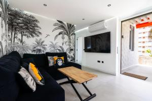 a living room with a black couch and a table at Apartamerica 341 LujoVista Mar in Playa de las Americas