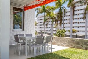 a white table and chairs on a balcony with palm trees at Apartamerica 341 LujoVista Mar in Playa de las Americas