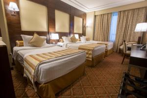 Habitación de hotel con 2 camas y escritorio en Ruve Al Madinah Hotel, en Medina