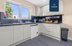 uma cozinha com armários brancos e uma janela em MUIRTON HOUSE, 4 Bed House, 4 Car Driveway, 2 Bathrooms, Smart TVs in every room, Fully Equipped Kitchen, Large Dining and Living Space, Rear Garden, Free WiFi, Mid to Long Stay Rates Available by SUNRISE SHORT LETS em Dundee