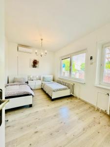 2 łóżka w białym pokoju z drewnianą podłogą w obiekcie Dovolenkovy dom v centre Pieštan w Pieszczanach