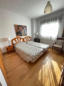 1 dormitorio con cama, ventana y suelo de madera en Piso centro de Granada junto al metro, en Granada