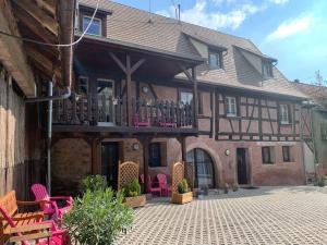 a large house with a balcony with pink chairs at Appartement Les Vendanges Parking privé Gites1596 in Beblenheim