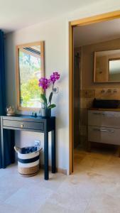 een badkamer met een tafel met een vaas met bloemen erop bij Le Cocoon Lodge du Gapeau & Massage in Solliès-Pont