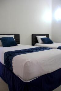 two beds with blue pillows in a bedroom at Hotel Juarez 70 in Colima