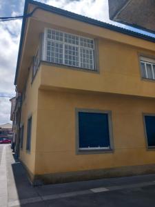 een geel gebouw met ramen aan de zijkant bij La Aurora in Camariñas