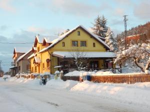 uma casa amarela está coberta de neve em Guest House Vila Frýdštejn em Frýdštejn