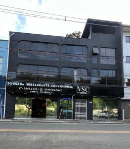 un edificio negro con un cartel delante en Pousada VSC, en São Francisco do Sul