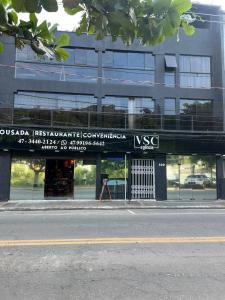 un edificio con un letrero al lado de una calle en Pousada VSC, en São Francisco do Sul