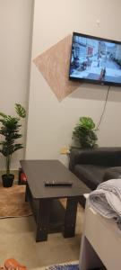 uma sala de estar com uma mesa e uma televisão na parede em MAMA DELIGHT GUEST ROOM em Abu Dhabi