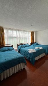 two beds in a room with blue sheets at Hotel Espindola in Tulcán +36 photos