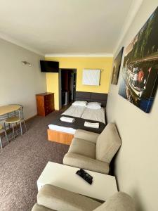 アウグストゥフにあるGościniec Rospuda 1のベッド2台とソファが備わるホテルルームです。