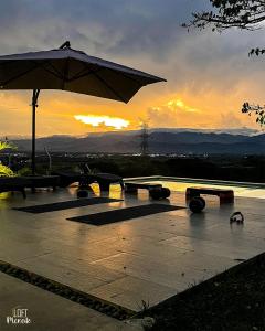 einen Sonnenuntergang mit einem Tisch und einem Regenschirm in der Unterkunft LoftMerak in Pereira
