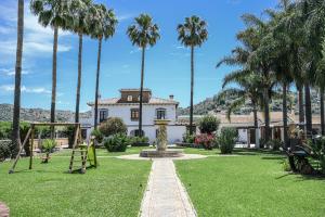 a house with palm trees and a playground at Amplia casa rural con precioso jardín cerca de Málaga capital. in Málaga