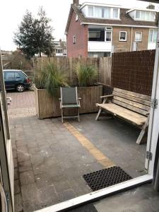 a view of a patio with a bench and a fence at Beach Cottage free parking in Noordwijk aan Zee