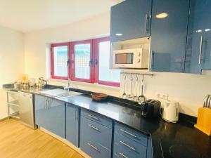 a kitchen with blue cabinets and a counter top at Vila D'Alba - Sem Stress in Albufeira