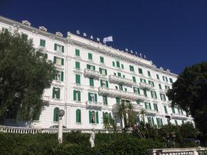 um grande edifício branco com persianas verdes em Grand Hotel & des Anglais em Sanremo