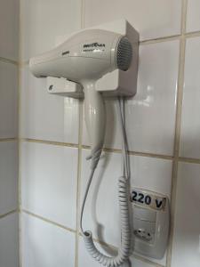 einen Fön, der in einem Badezimmer an einer Wand hängt in der Unterkunft Bangalô 5 - Praia de Guaratiba-prado/ba in Prado