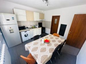 a kitchen with a table and chairs and a kitchen with a refrigerator at Casa Aris in Călimăneşti