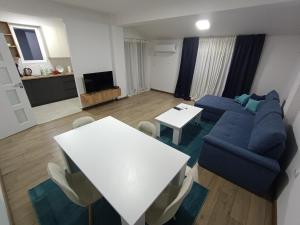 Grand Apartments Strumica في ستروميكا: غرفة معيشة مع أريكة زرقاء وطاولة