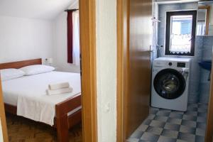 a bedroom with a bed and a washing machine at House Private beach in Bibinje