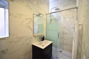 La salle de bains est pourvue d'un lavabo et d'une douche en verre. dans l'établissement Jardin Secret - Élégance Urbaine, 