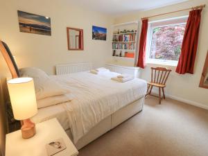 1 dormitorio con 1 cama y 1 mesa con lámpara en Striding Home, en Ambleside