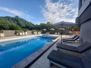a swimming pool with chairs and an umbrella at Hotel Raices Aconcagua in Mendoza