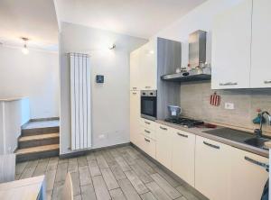 a kitchen with white cabinets and a staircase at Aria di Borgo in Nettuno