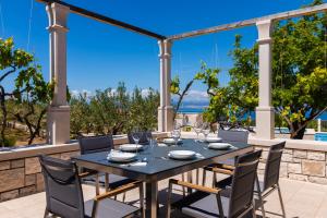 a table and chairs on the patio of a house at VILLA AGAPE - Stone villa on 15k m2 olive grove - Incredible 360 view in Mirce