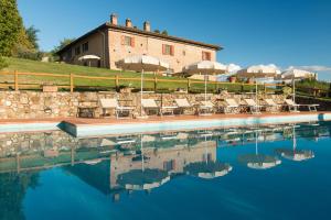 une piscine d'eau avec des chaises et un bâtiment dans l'établissement Il Coltro, à San Gimignano