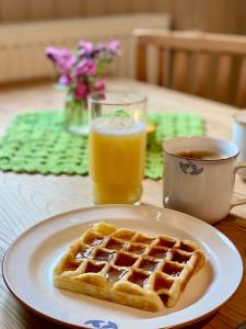 a waffle on a plate on a table with orange juice at Ekologiska Fru Gran B&B i Tiveden in Gårdsjö