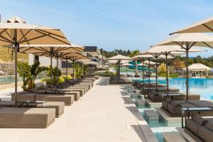 a row of chairs and umbrellas next to a pool at Trypiti Resort Blue Dream Palace and Hive Water Park in Limenaria