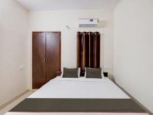 Schlafzimmer mit einem Bett und einem Holzschrank in der Unterkunft OYO Flagship Valasaravakkam in Chennai