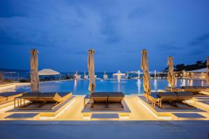 a swimming pool with chaise lounge chairs and umbrellas at Trypiti Resort Blue Dream Palace and Hive Water Park in Limenaria