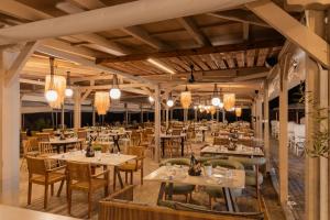 a restaurant with tables and chairs and chandeliers at Trypiti Resort Blue Dream Palace and Hive Water Park in Limenaria