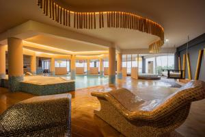 a lobby with chairs and a pool in a building at Trypiti Resort Blue Dream Palace and Hive Water Park in Limenaria