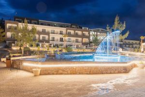 a hotel with a fountain in front of a building at Trypiti Resort Blue Dream Palace and Hive Water Park in Limenaria